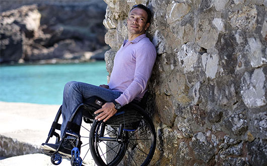 Man in wheelchair leaning against wall