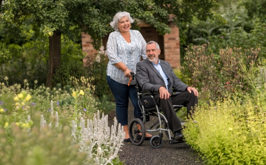 women pushing man in wheelchair outdoors