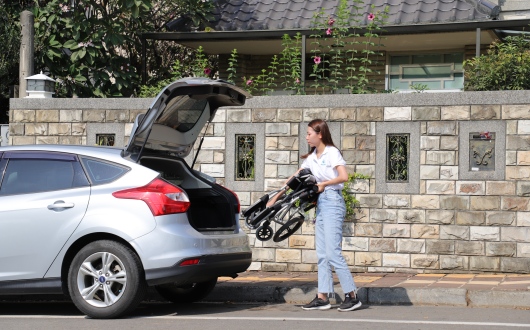 Woman placing folded wheelchair into car
