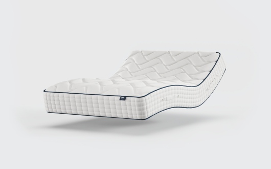 A modern, white mattress with a quilted pattern appears to float and is bent in an S-shape, suggesting flexibility or adjustability, against a plain white background—perfectly capturing the innovative design of the Opera Gel Pro 4000.