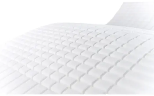 Close-up of a white, textured surface with a grid-like pattern of raised, rectangular shapes, possibly part of an Opera Serene Profiling Mattress or cushion.