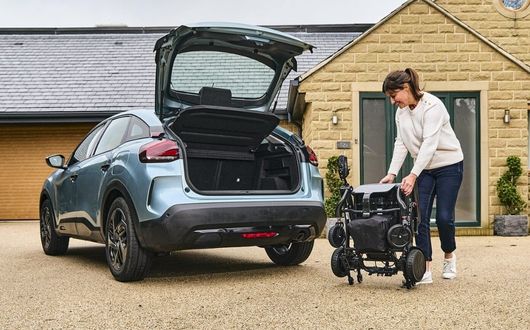 Photon powerchair folded and being placed in car boot