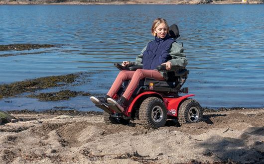 Girl using Extreme X8 powerchair on sand.