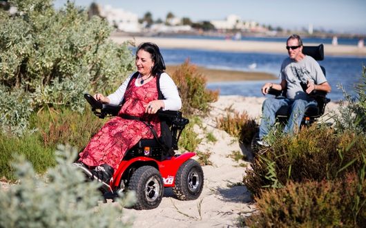 Woman using Extreme X8 powerchair on sand.