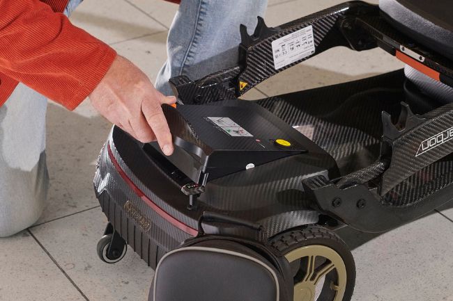 Man holding a mobility scooter battery.